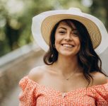 Young woman wearing dress and hat walking in park